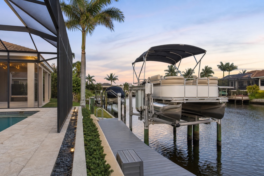 Pontoon boat raised on a lift beside a screened lanai